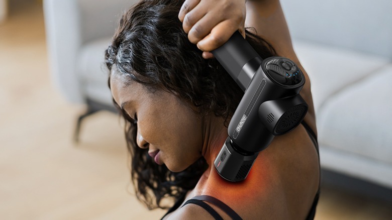 Woman using Thermacool Massage Gun on shoulder