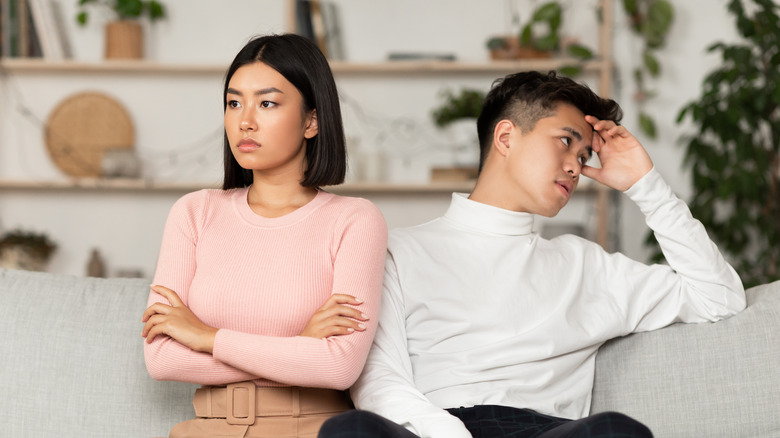 An Asian couple sitting next to each other but looking away from each other