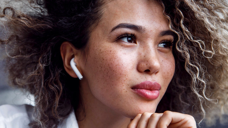 Woman wearing earbuds and displaying freckles