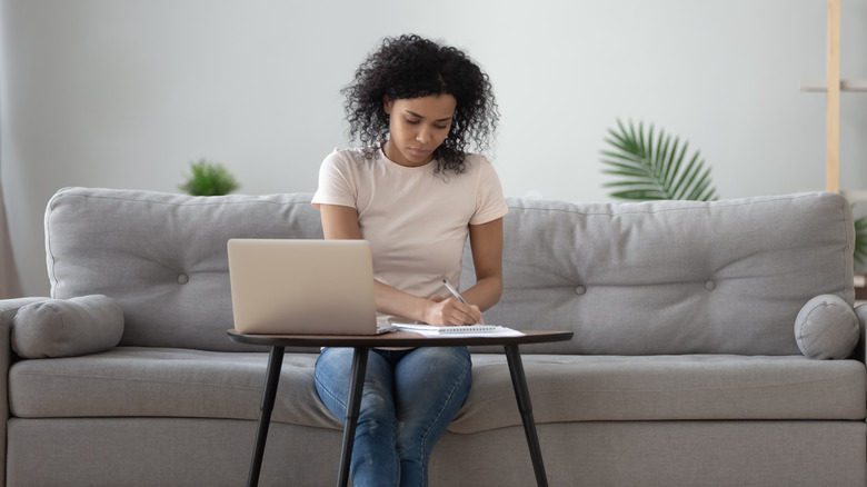 woman sitting on sofa writing notes