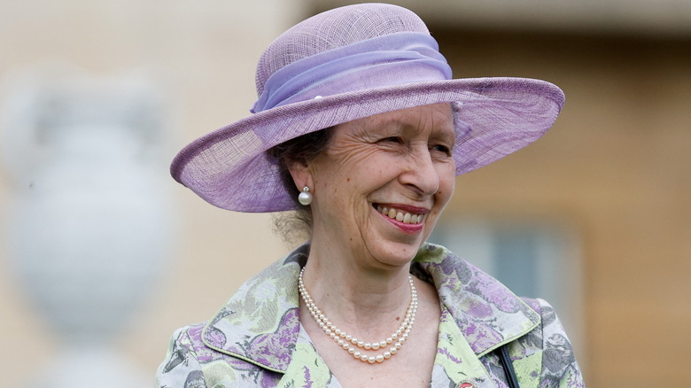 Princess Anne smiling in purple hat