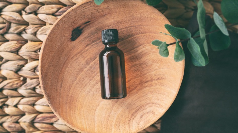 An essential oil bottle in a wooden basin