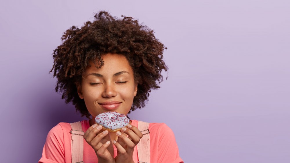 woman savoring the smell of a donut