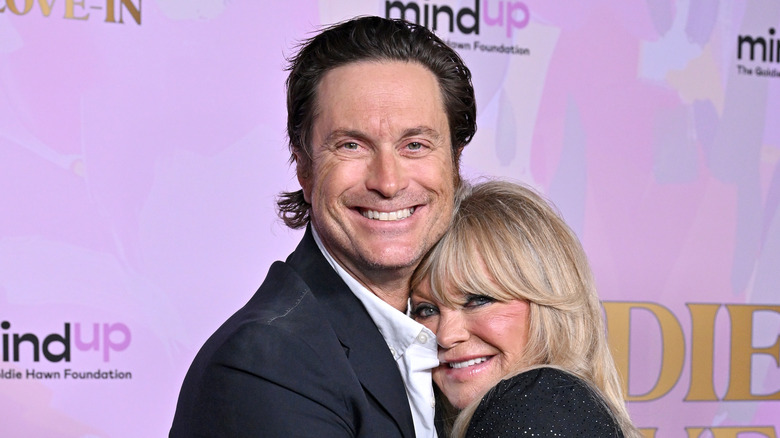 Oliver Hudson and Goldie Hawn smiling and hugging at an event