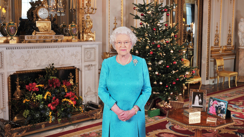 Queen Elizabeth II stands in front of a Christmas tree 