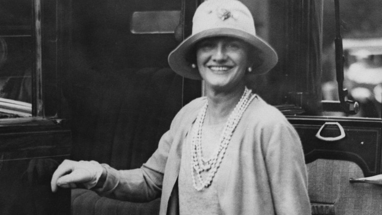 Coco Chanel smiling next to car