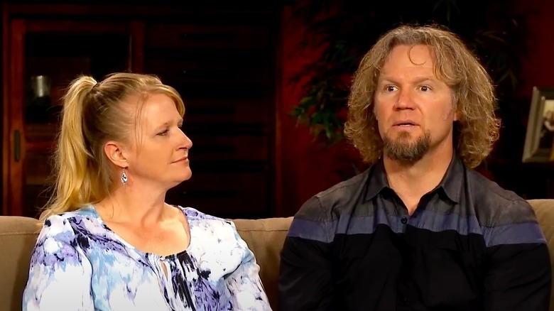 Christine and Kody Brown sitting on a couch in Sister Wives