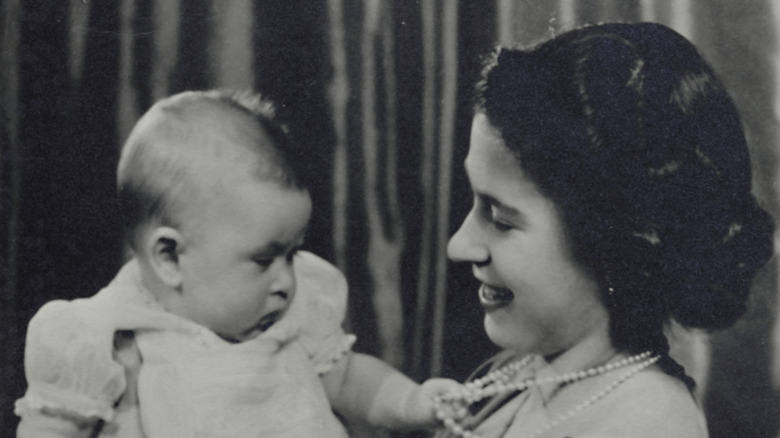 King Charles as a baby being held by Queen Elizabeth