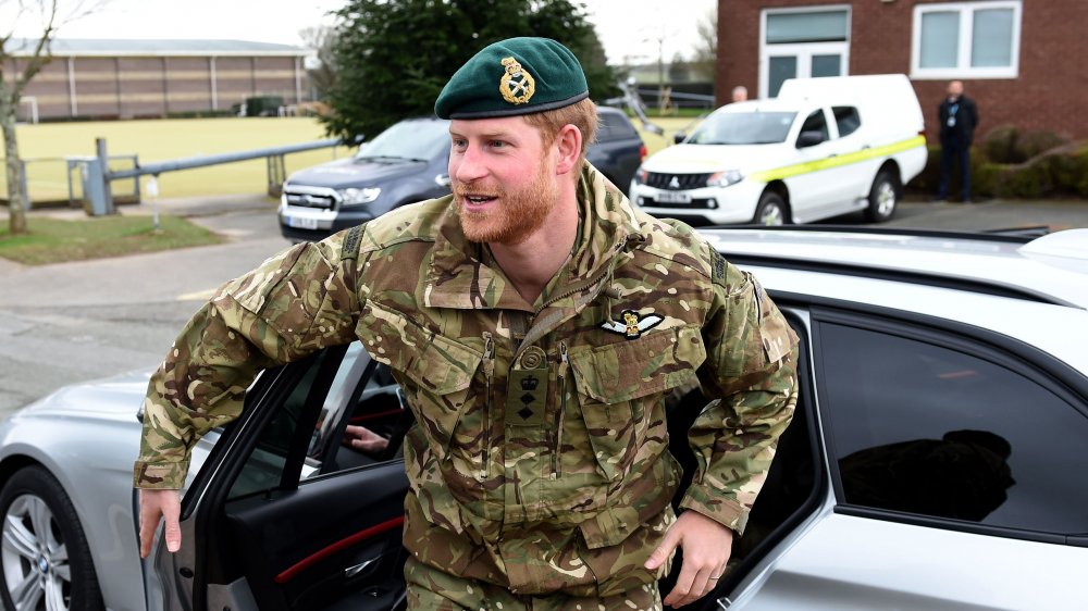 Prince Harry in his military fatigues exiting a vehicle