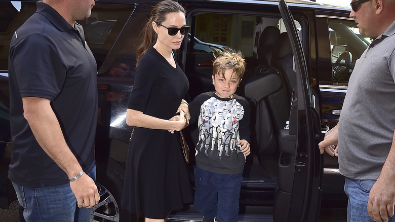 Young Knox Jolie-Pitt exiting car helped by Angelina Jolie surrounded by two bodyguards