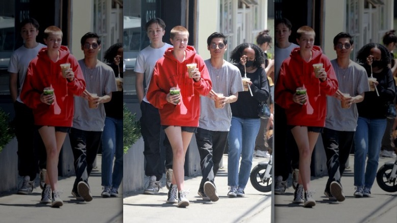 Knox Jolie-Pitt walking on a sidewalk with his older siblings holding coffees