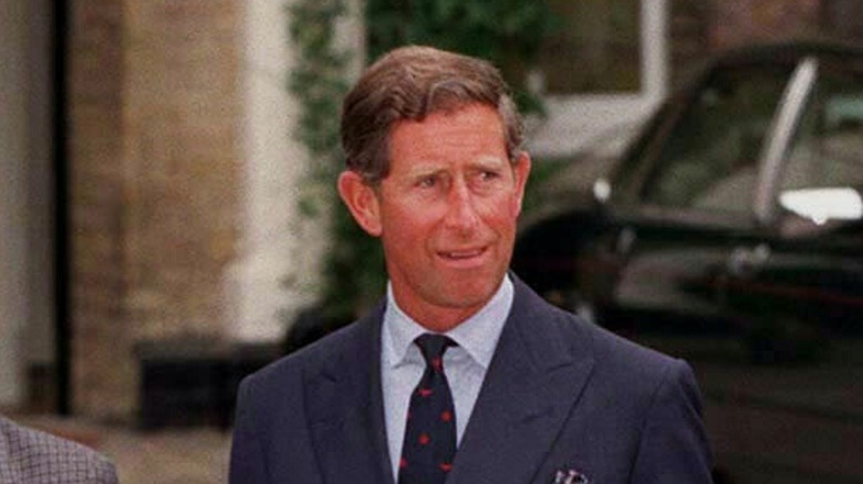 Prince Charles standing in front of a car