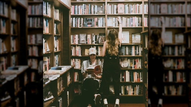 man reading while girlfriend chooses book