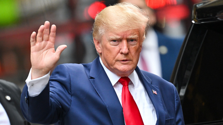 Donald Trump waving and wearing red tie