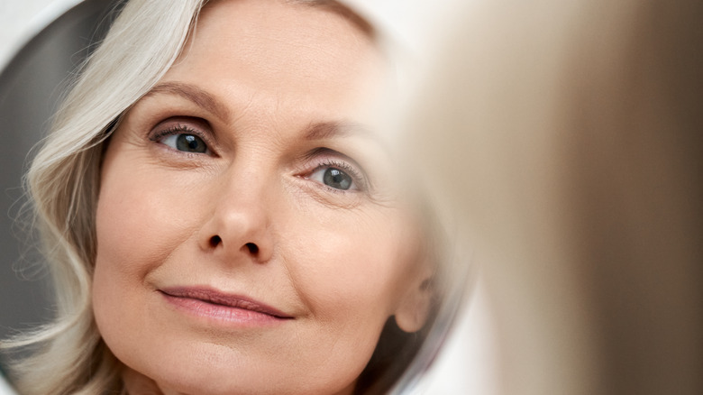 mature woman smiling into mirror