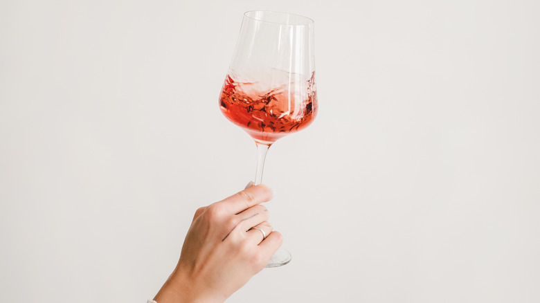 Woman's hand holding and turning glass of rose wine