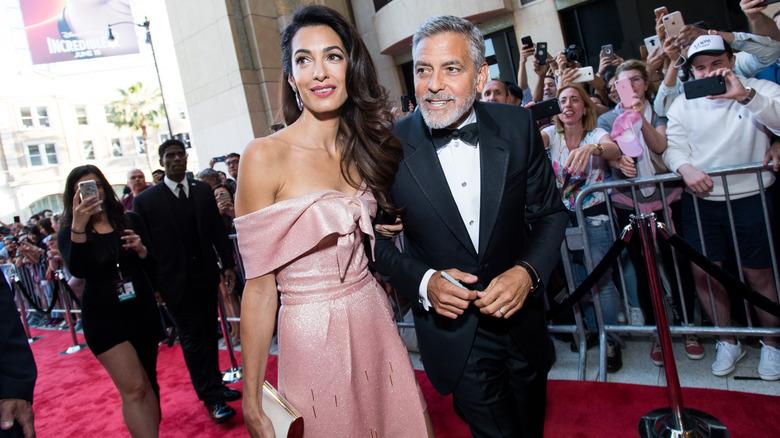 Amal and George Clooney surrounded by cameras on the red carpet