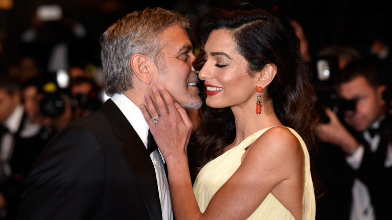 George Clooney whispering into Amal Clooney's ear