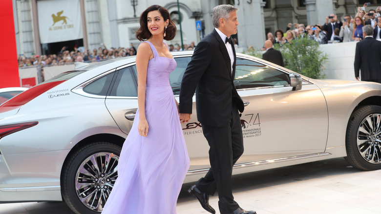 Amal and George Clooney walking by a car