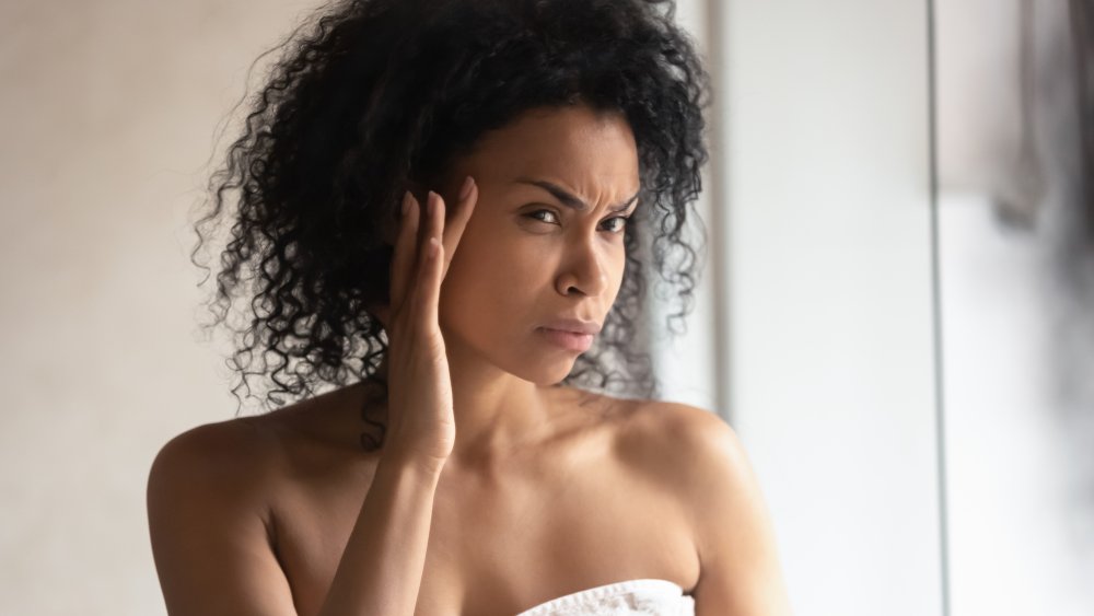 woman looking at blackheads in bathroom mirror