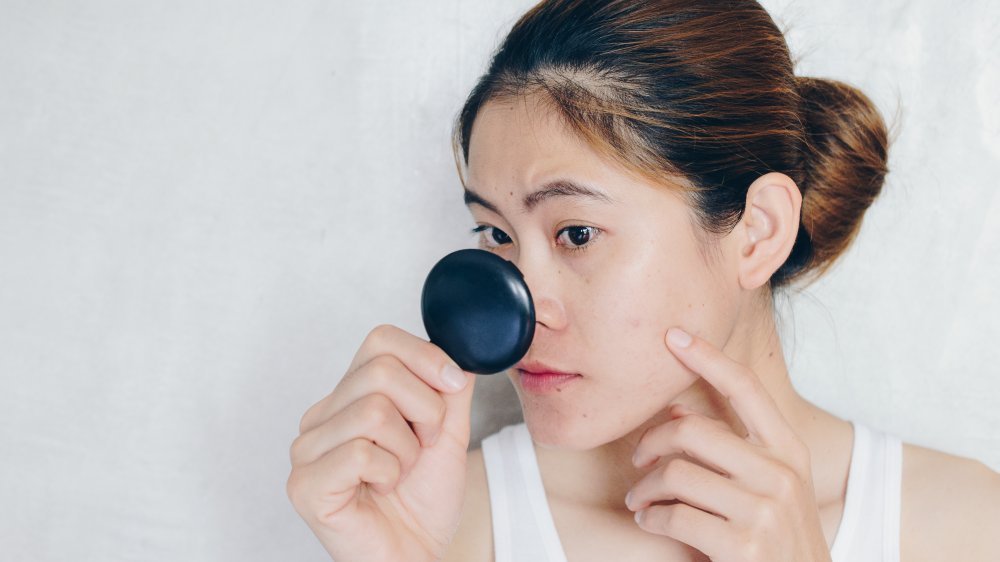 woman looking blackheads in mirror