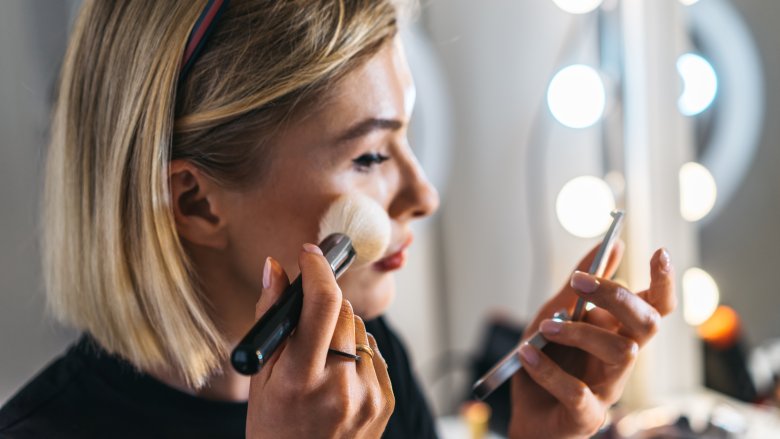 Blonde woman applying make up