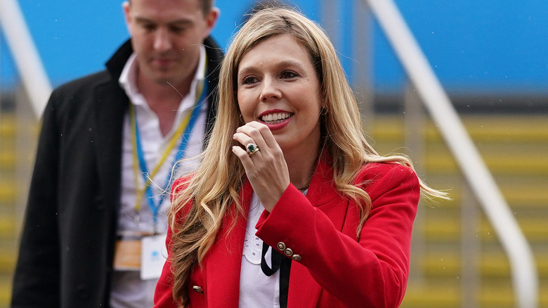 Carrie Johnson smiling, wearing red jacket