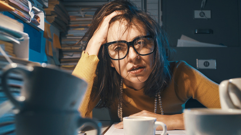 Woman surrounded by files crashing from caffeine 