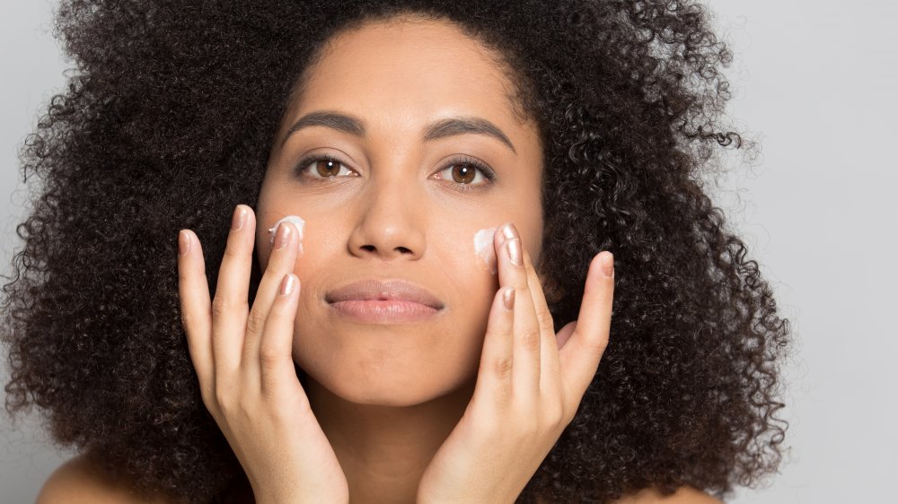 Woman applying cream to her face