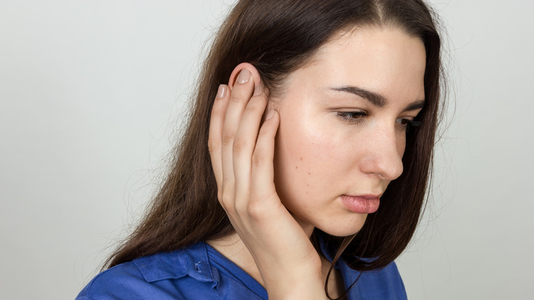 woman covering/holding ear