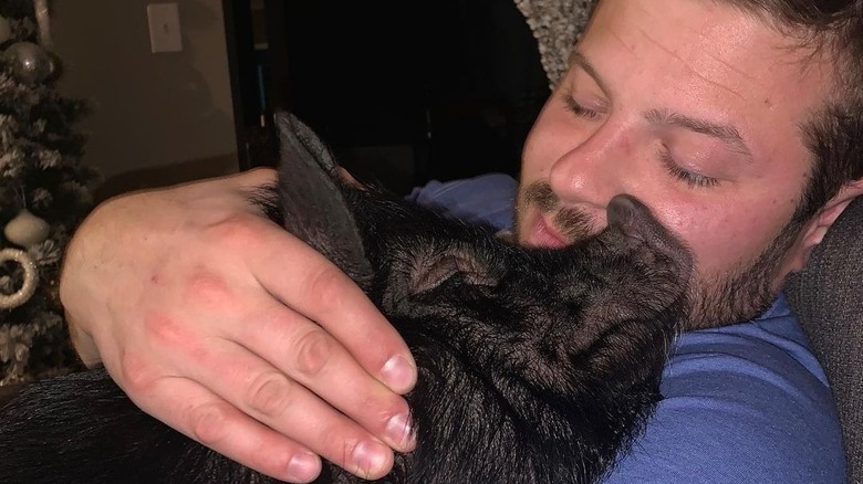 Cory Miller cuddles his pet pig