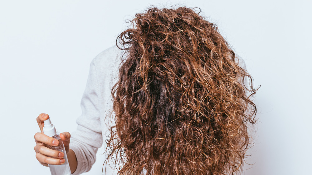 A woman spraying her curly hair