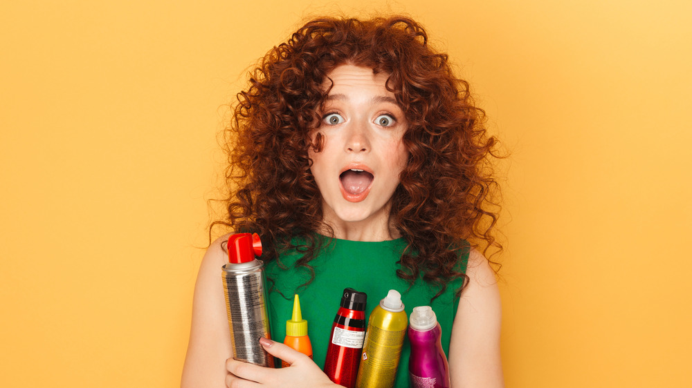 A woman with curly red hair holding products