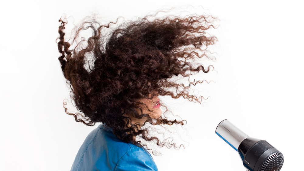 A woman blow drying her curly hair