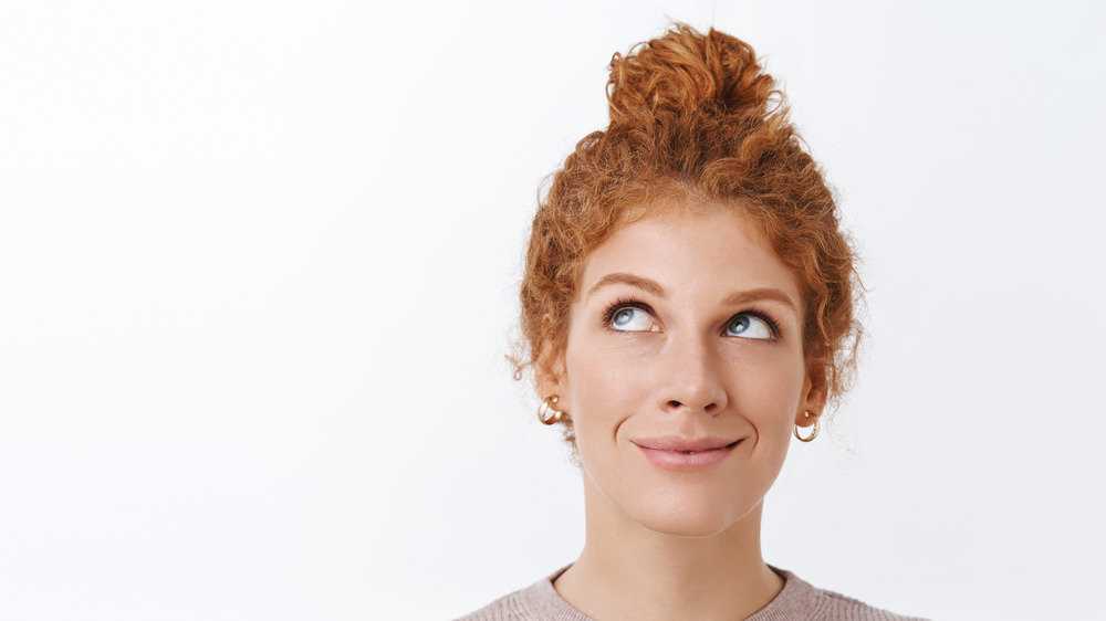 A redheaded woman with her curly hair in a bun