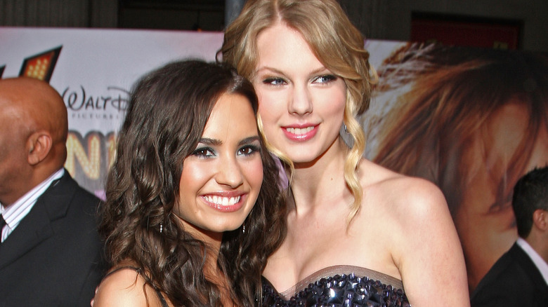 Demi Lovato and Taylor Swift smile in dresses.