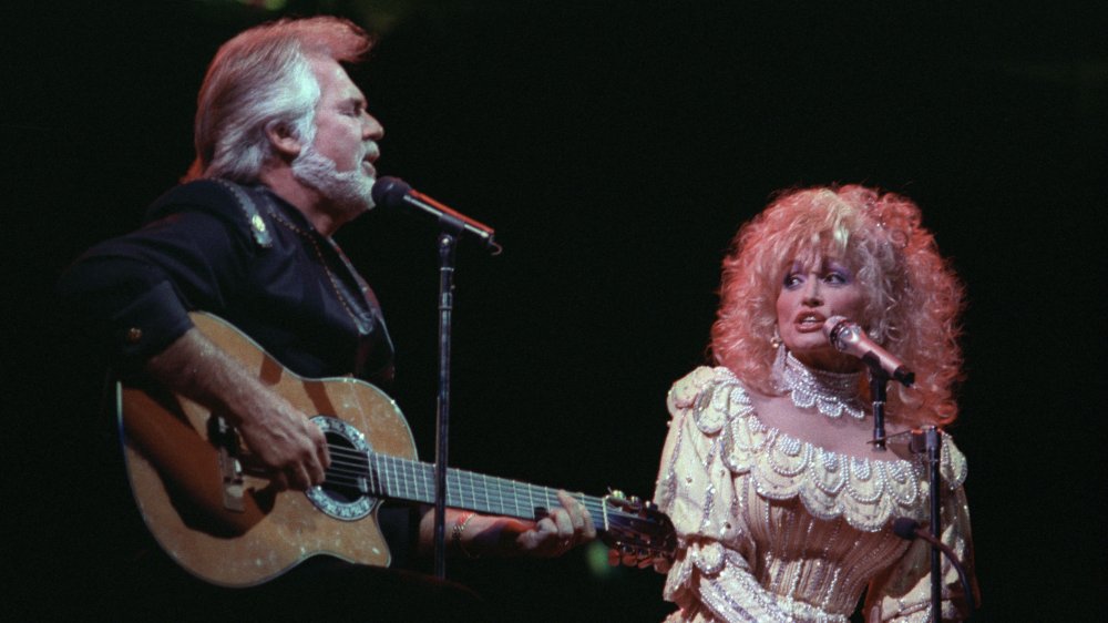 Kenny Rogers and Dolly Parton singing on stage, on stools