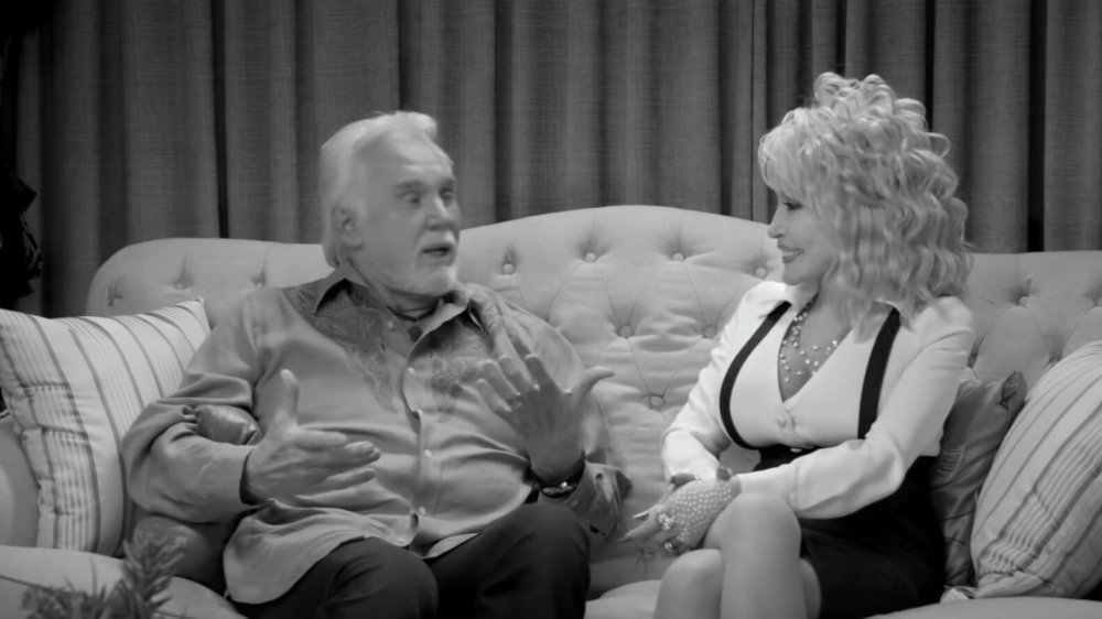 Kenny Rogers and Dolly Parton sitting on a couch, talking