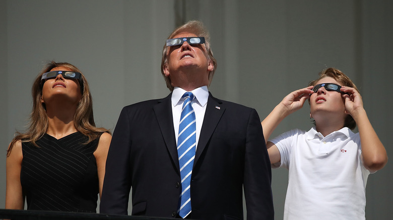 Melania, Donald, and Barron Trump looking at an eclipse