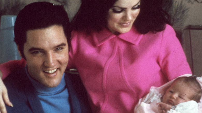 Priscilla Presley in pink coat with baby 