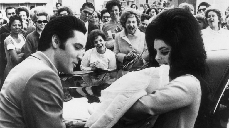 Crowd watching Elvis and Priscilla Presley with baby