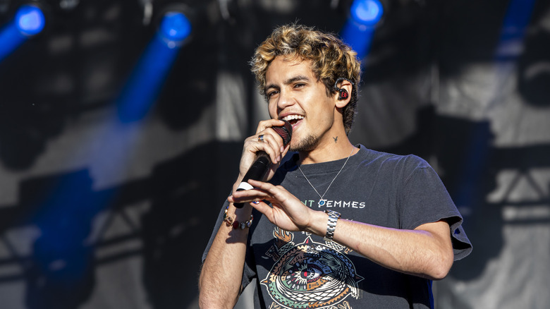 Dominic Fike holding a microphone and singing