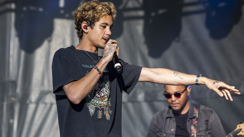 Dominic Fike singing into a handheld microphone and pointing