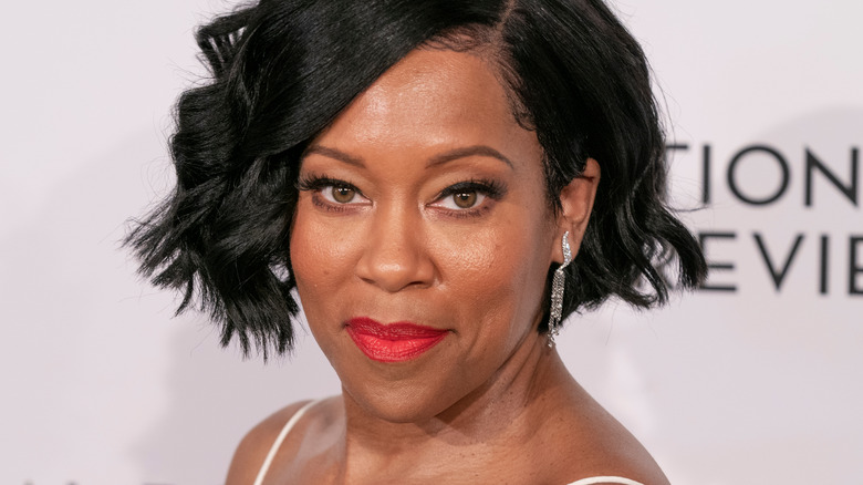 Regina King smiles with earrings and red lips