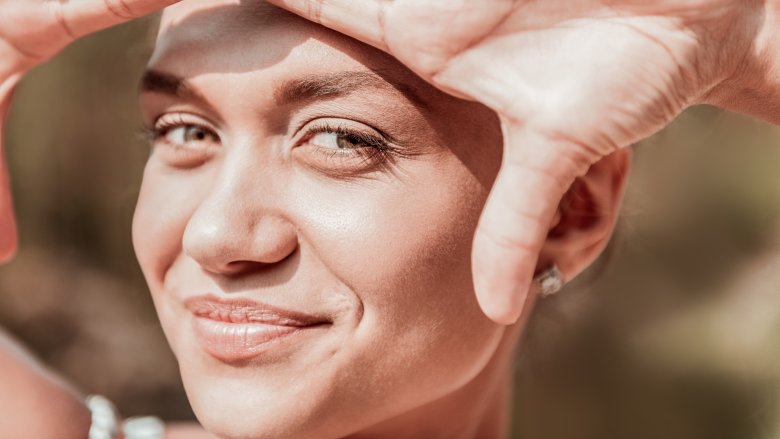 woman with green eyes shielding face from sun