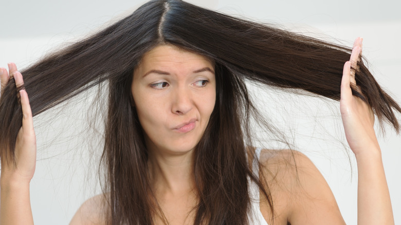 Woman holding her hair looking doubtful