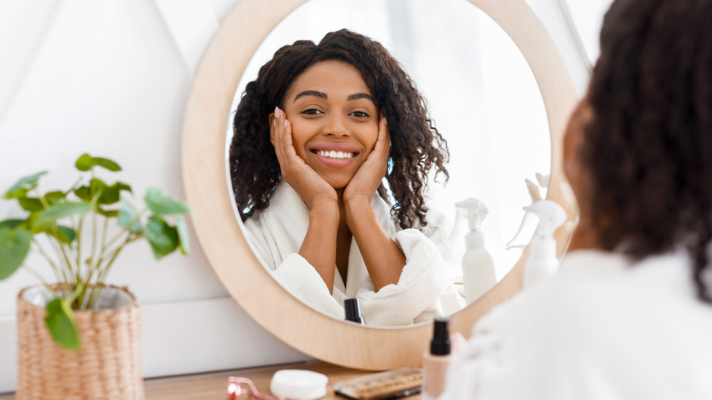 Woman applying skincare product in mirror