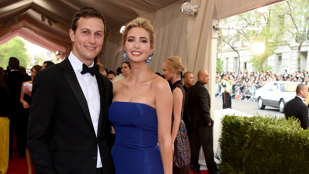 Jared Kushner in a black tux, Ivanka Trump in a blue dress, smiling while arm in arm