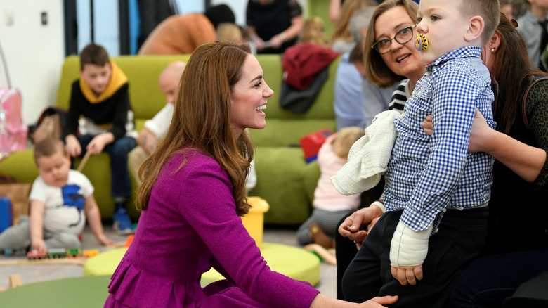 Kate Middleton smiling at child, crouching