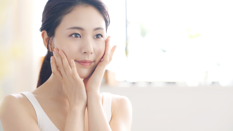 A woman touching her face with her hands.